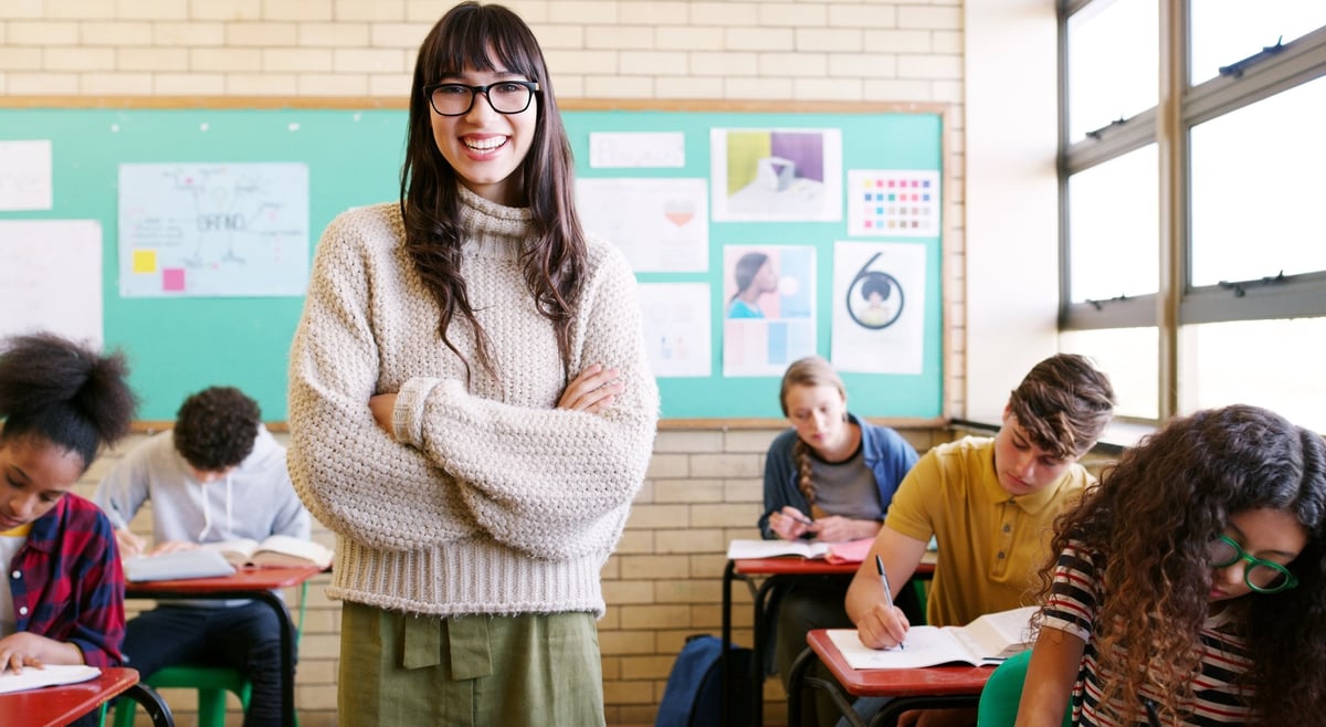 Cheerful teacher giving a lesson to a group of students inside a school