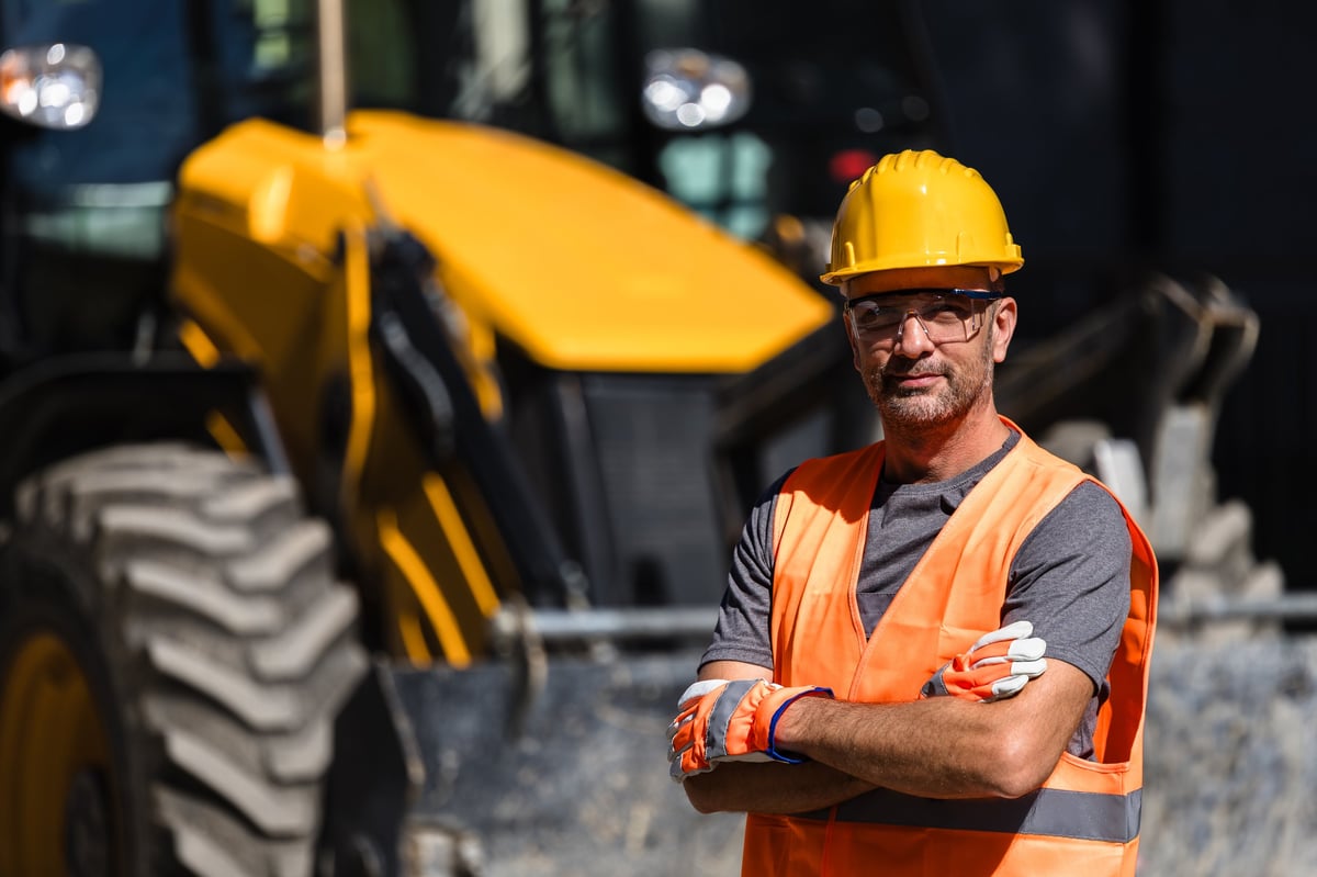 Construction worker wearing an orange vest and hard hat at a construction site