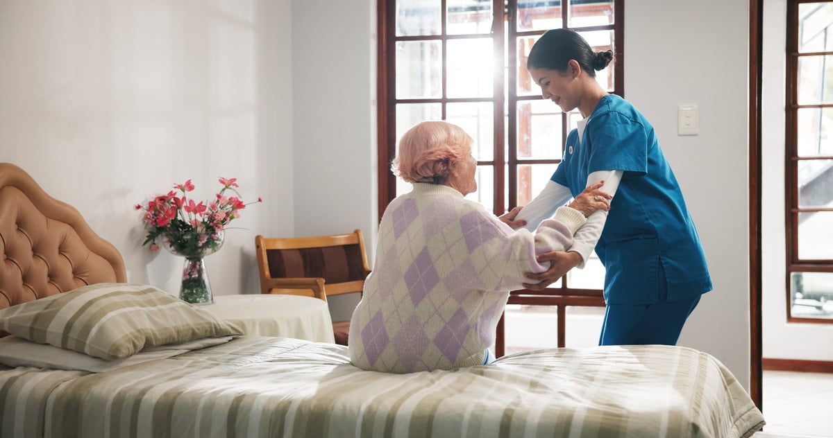 Caregiver assisting a senior woman in a care home setting