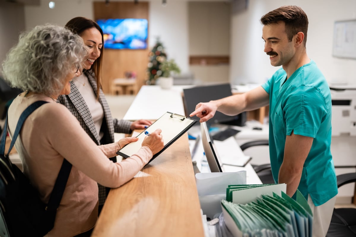 Staff assisting visitors completing the check-in process at a reception desk