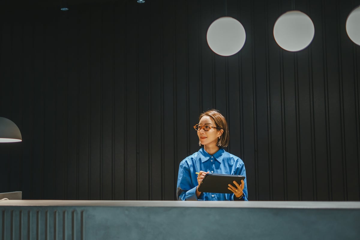 Professional woman using a digital tablet at a modern reception desk in a contemporary office setting